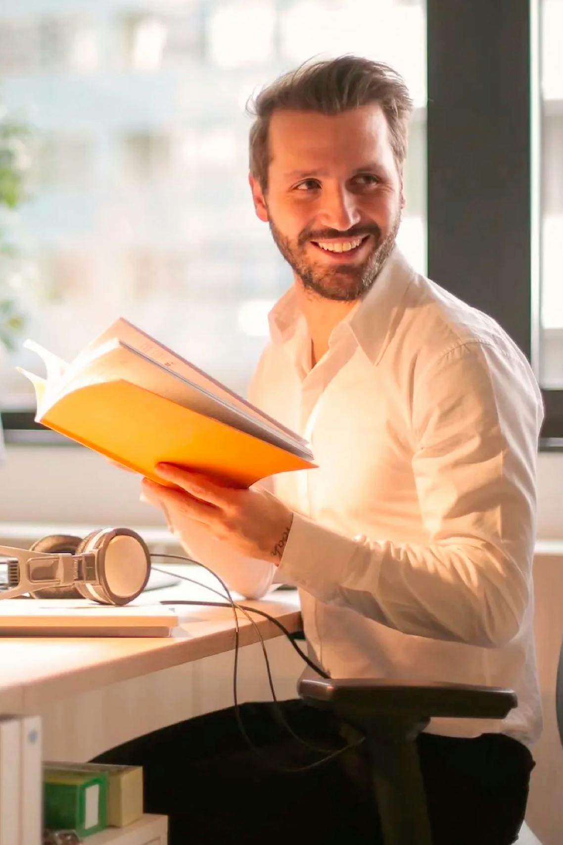 Man sitting at desk holding a book
